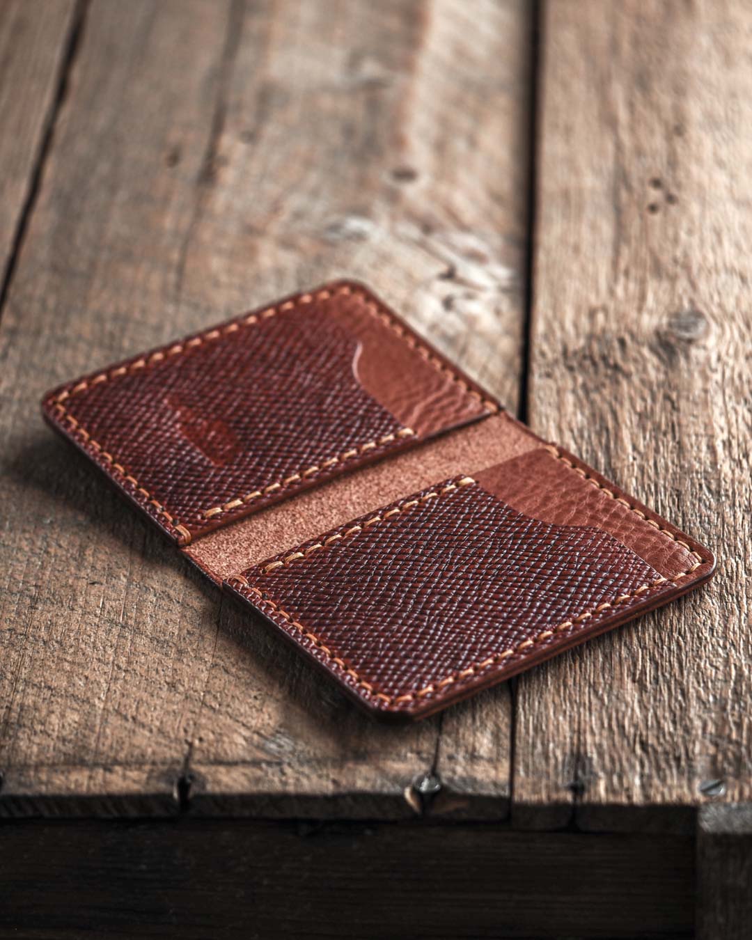 Brown bifold leather wallet open on a wooden surface