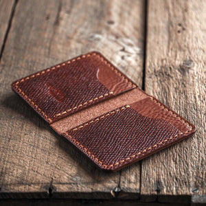 Brown bifold leather wallet open on a wooden surface