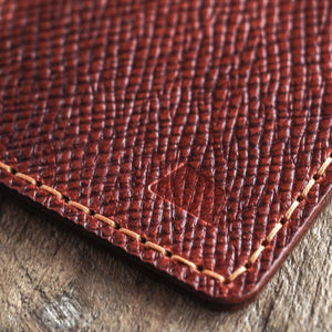 Close-up of a brown leather wallet with visible stitching and a logo