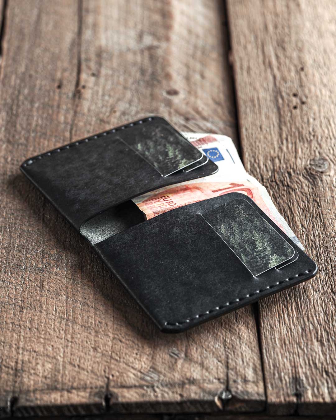 Handmade leather bi-fold wallet for men. Minimalist and rugged style. Traveler's wallet black open in use