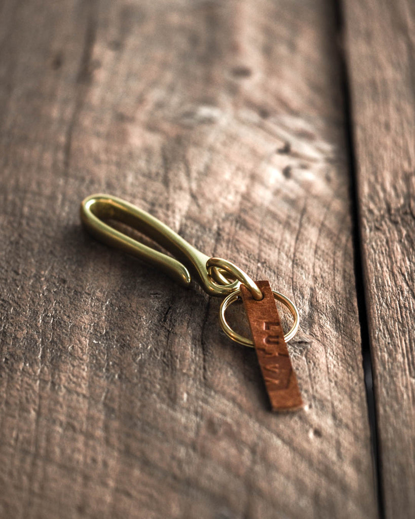 Brass keychain with leather tag on a wooden surface